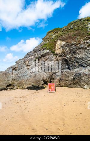 A danger sign warning about unstable cliffs and falling rocks on the beach below cliffs on Gt Great Western Beach in Newquay in Cornwall in the UK. Stock Photo