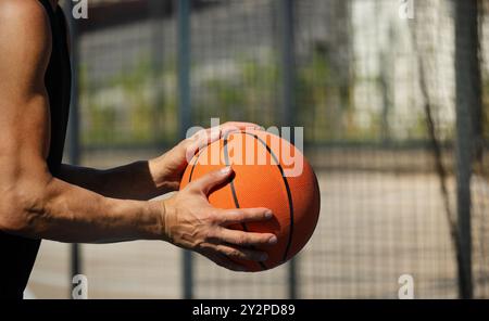 Basketball orange ball in mans hand on sport court. Sport training. Team sport. Copy space. Close up. Basketball Throwing Technique. Stock Photo