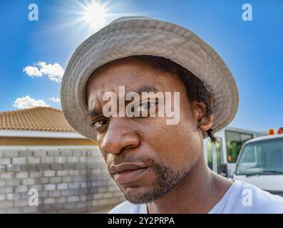 single young african man with dreadlocks and a hat, outdoors in the city, blue sky sunny day Stock Photo