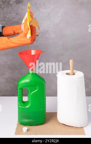 A green plastic bottle is filled with dishwashing liquid from a refill Stock Photo
