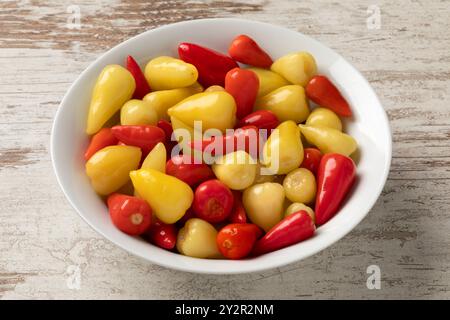 Bowl with small pickled spicy red and yellow mexican peppers close up Stock Photo