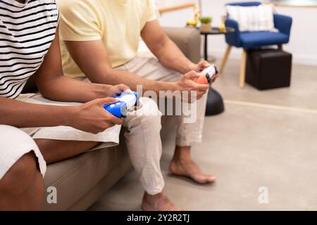 Couple relaxing on a sofa, engaged in playing video games together in a cozy, well-decorated living room Stock Photo