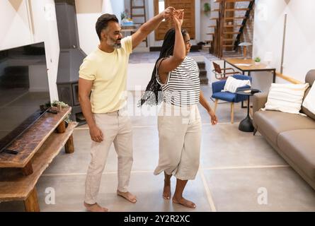 A cheerful couple enjoys a playful dance in their stylish living room, surrounded by contemporary furniture and a warm, inviting decor Stock Photo