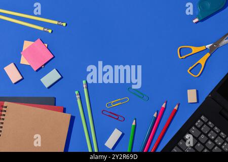 Top view of a vibrant selection of school supplies, including pencils, erasers, paper clips, and notebooks, neatly arranged on a bright blue backgroun Stock Photo