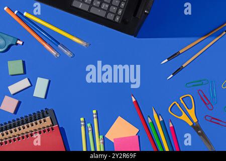Top view of a vibrant selection of school supplies, including pencils, erasers, paper clips, and notebooks, neatly arranged on a bright blue backgroun Stock Photo