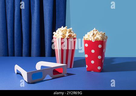 Colorful popcorn boxes with 3D glasses, ready for movie night on a blue background Stock Photo