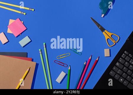 Top view of a vibrant selection of school supplies, including pencils, erasers, paper clips, and notebooks, neatly arranged on a bright blue backgroun Stock Photo