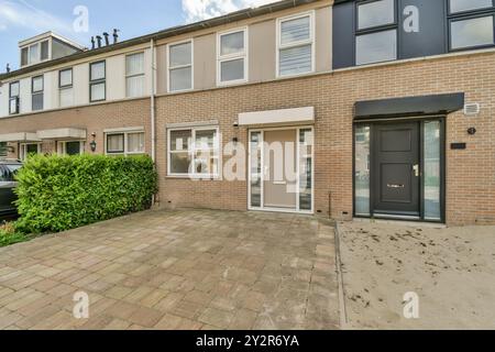 A daytime view of terraced houses featuring brick walls, white windows, and dedicated parking spaces in a suburban neighborhood. Stock Photo