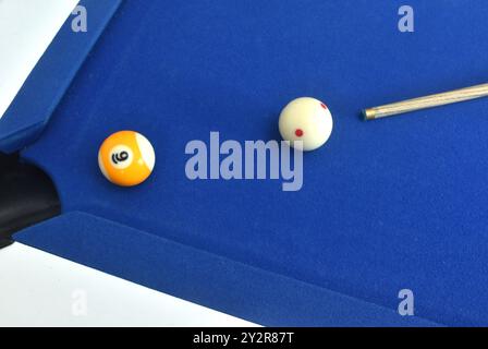 cue stick pointing on white billiard ball ready for shooting nine ball to hole on blue pool table Stock Photo
