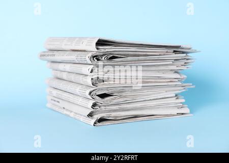 Stack of newspapers on light blue background Stock Photo