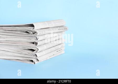 Stack of newspapers on light blue background, space for text Stock Photo