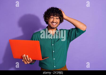 Photo portrait of young upset indian freelancer guy with laptop overworked today feel headache isolated on violet color background Stock Photo