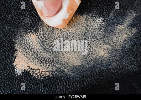 Cleaning a leather surface with a cloth to remove dirty cosmetic stain on black leather surface. High quality photo Stock Photo