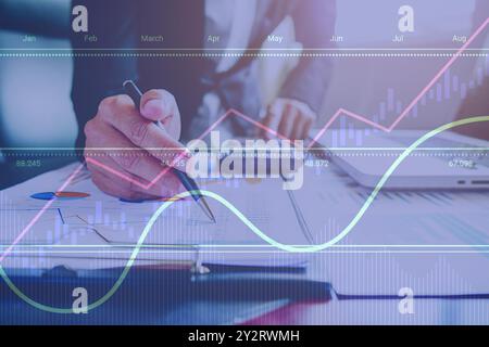 Businessman analyzing financial documents and charts with a digital data overlay representing growth and market trends. Stock Photo