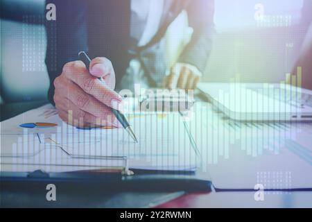 Businessman analyzing financial documents and charts with a digital data overlay representing growth and market trends. Stock Photo