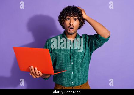 Photo of mexican upset guy with wavy haircut wearing green casual shirt holding laptop confused code crashed isolated on violet color background Stock Photo