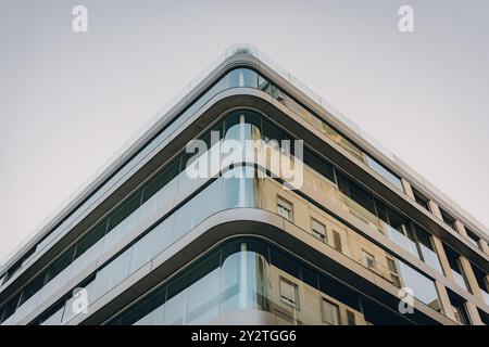 Glass-walled office building with rounded edges, featuring contemporary architectural style in an urban area. Stock Photo