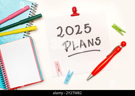 Notepads, markers and a sheet of paper with 2025 plans phrase written on it on a white background Stock Photo