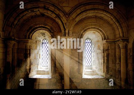 Sunlight streaming through two arched windows in an ancient stone building, creating a serene and historic atmosphere. Stock Photo