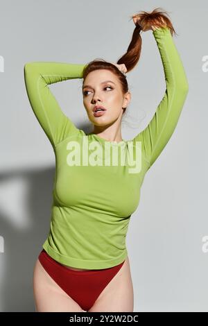 Confident red haired woman styled in chic attire showcases her unique look. Stock Photo
