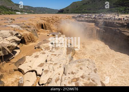 Hukou Waterfall on the Yellow River in China with tourists observing from the cliffside on a clear day Stock Photo