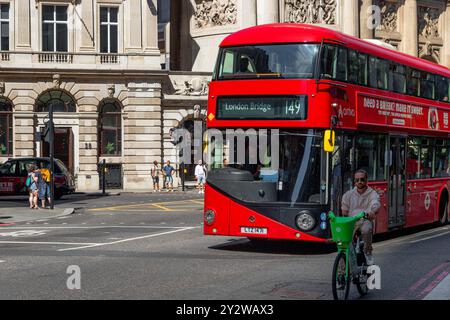 A London double decker Bus 149 about to pass a cyclist riding a Lime hire bike on Bishopsgate in The City Of London, London, UK Stock Photo
