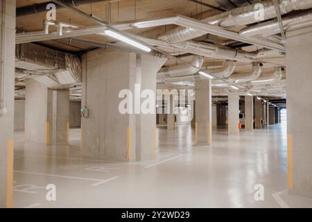 A clean, well-lit underground parking garage with concrete pillars Stock Photo