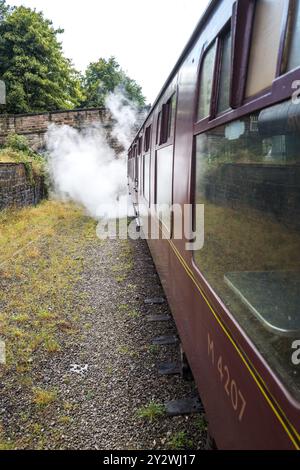 Steam locomotive operating on the Ecclesbourne Valley railway pulling out of Wirksworth railway station pulling coach with visitors. Stock Photo