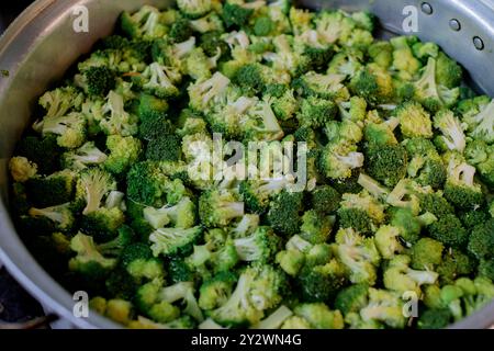 A close-up view of fresh broccoli florets in a large metal pot ready for cooking. Stock Photo