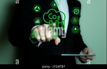 A business professional interacting with a digital interface showing CO2 reduction icons and symbols. Stock Photo