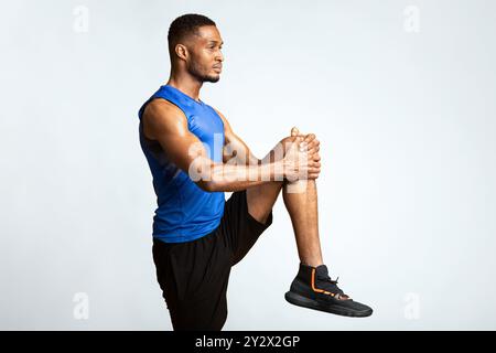 Young black sportsman walks highly holding knee Stock Photo