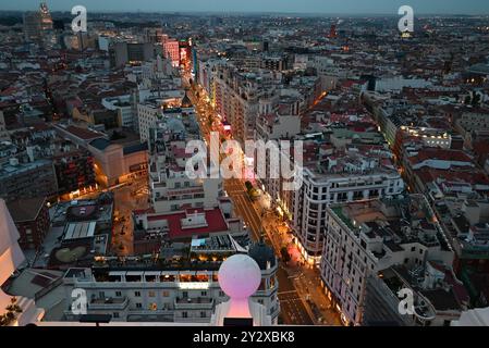 Aerial view of Gran Via street in Madrid at dusk, showing the vibrant cityscape with illuminated buildings and busy streets. Stock Photo