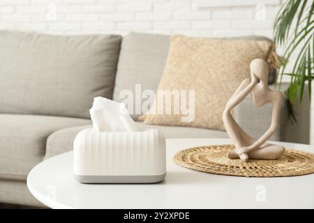 Tissue in ceramic holder on coffee table with human figure in living room. Closeup Stock Photo