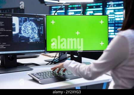 Programmer doing checkup on green screen computer in server room used for artificial intelligence workloads. IT professional inspecting neural network data center facility with chroma key PC Stock Photo
