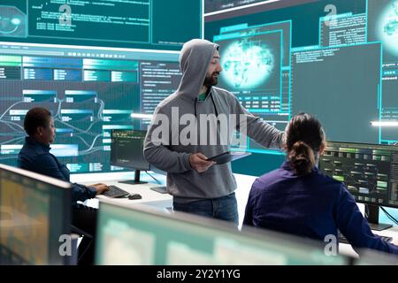 Governmental hackers analyzing data for cyber threat detection, looking at a big screen in high tech office. Highlight cyber intelligence, online security and prevention of digital threats. Stock Photo