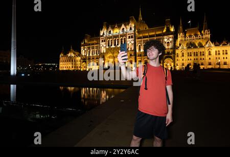 Budapest, Hungary. August 24, 2022. Amazing night shot of the parliament. The lighting enhances the beauty and elegance of the building. A young man t Stock Photo