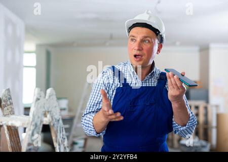 Foreman using smartphone, recording voice message Stock Photo