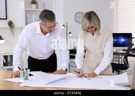 Architects making engineering drawing at wooden table in office Stock Photo
