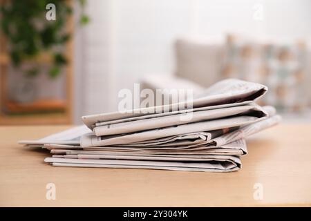 Stack of newspapers in different languages on table indoors Stock Photo