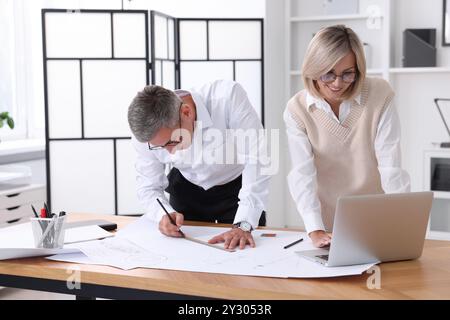 Architects making engineering drawing at wooden table in office Stock Photo