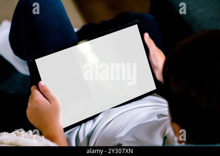 Boy holding a tablet computer with blank screen for mockup. White screen for place your design. Stock Photo