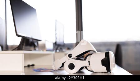 VR headset on desk in modern office with computers, ready for creative work Stock Photo