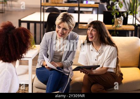 Collaborating on creative writing, multiracial women discussing ideas with colleague in office Stock Photo
