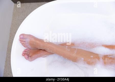At home, Relaxing in bathtub, woman soaking feet in bubble bath for spa treatment Stock Photo