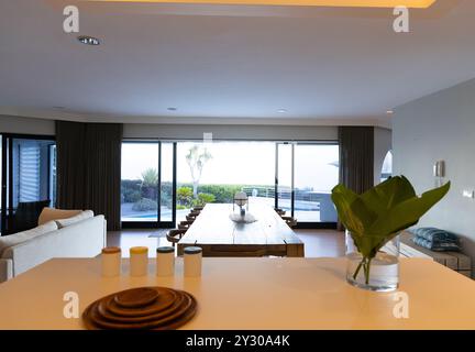 At home, Large dining table in modern living room with panoramic windows, creating serene ambiance Stock Photo