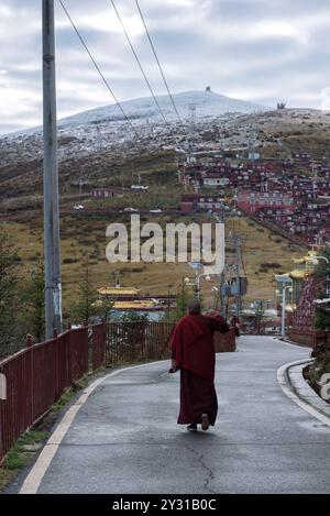 A Buddhist Lama walking on the road of Larung Gar Buddhist Academy , in Serta County, Garze Tibetan Autonomous Prefecture, Sichuan , China. Stock Photo