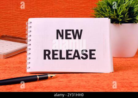 Text NEW RELEASE on a blank notepad page on an orange back Stock Photo