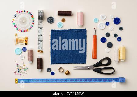 Sewing supplies and denim fabric arranged on a workspace for clothing alterations in a bright setting Stock Photo