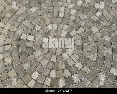 Natural grey cobbles or paving stone slab forming circular pattern for outdoor garden flooring finishes. Stock Photo