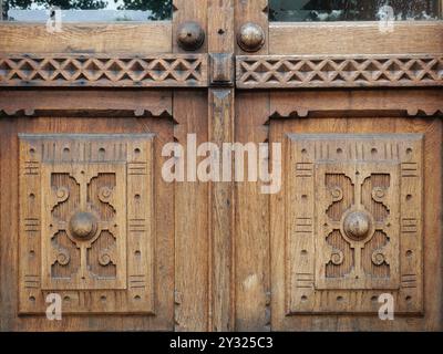 A detailed view of a highly ornate wooden door showcases intricate carvings and traditional craftsmanship, reflecting historical woodwork. Stock Photo